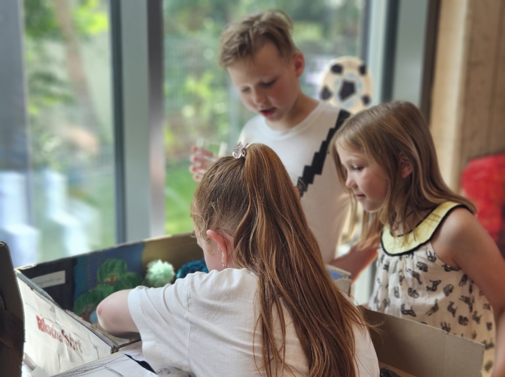 Abschlussfeier Sprachcamp Drei Kinder arbeiten an Diorama von Stadtteil Malstatt