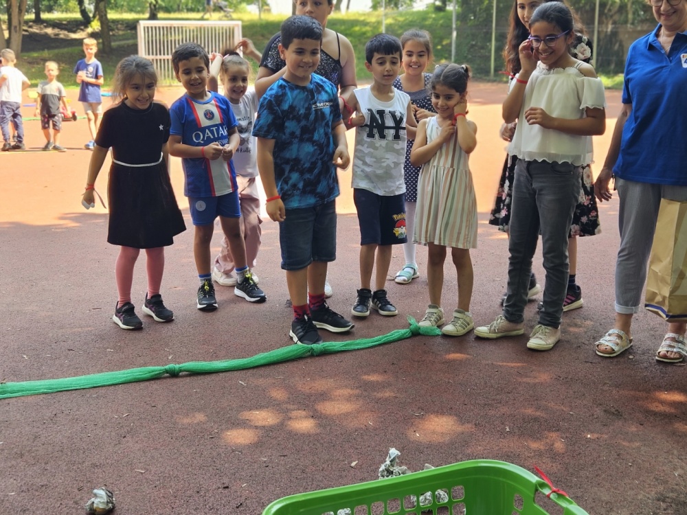 Kinderolympiade Gruppe von Kindern steht vor grüner Ziellinie auf Sportplatz