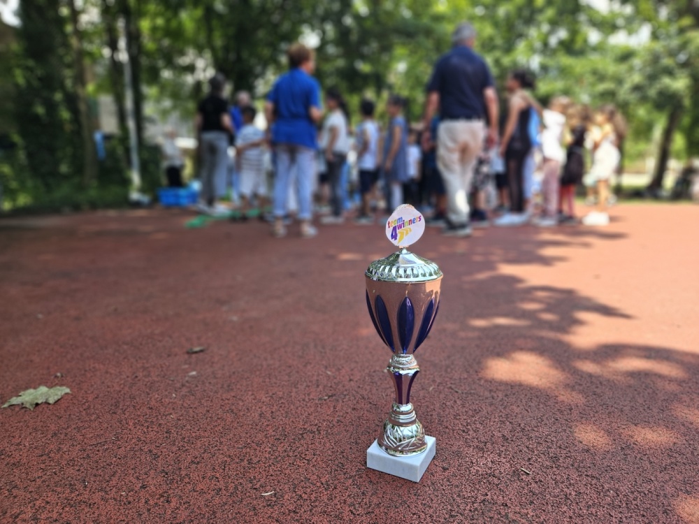 Pokal von Team4Winners Saar e.V. Pokal von Team4Winners Saar e.V. steht auf Boden, Kinder und Erwachsene auf Sportplatz im Hintergrund zu sehen