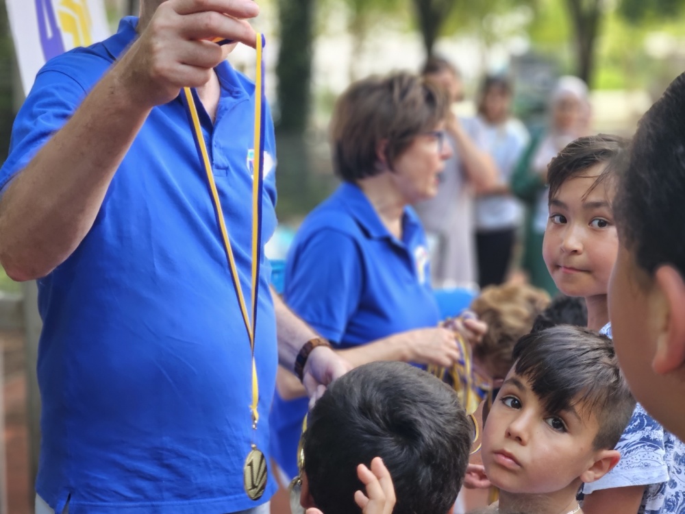 Kinderolympiade Erwachsene mit blauen Trikots verteilen Medaillen an Kinder