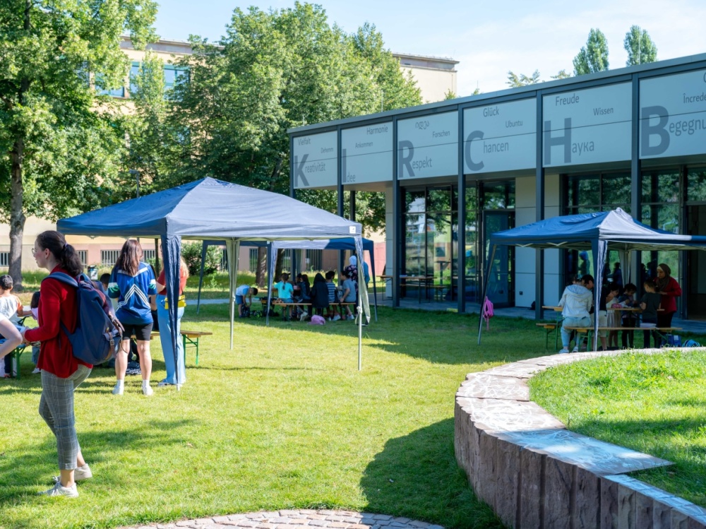 Sprachcamp 2024 Blaue Zelte auf Außengelände der Bildungswerkstatt, Gebäude im Hintergrund zu sehen