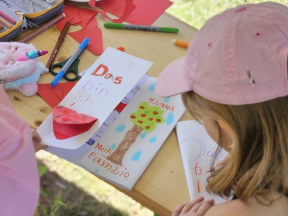 Sprachcamp 2024 Kinder nehmen an kreativen Aktivität teil, Bastelmaterial auf Tisch ausgelegt