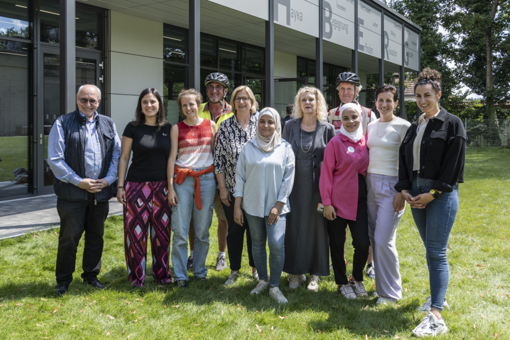 Besuch von Ministerpräsidentin Anke Rehlinger Gruppe von Menschen steht vor Bildungswerkstatt für Fotoaufnahme: v.l.n.r.: Thomas Emser, Sprachförderlehrkräfte, Guido Vogel-Latz, Anke Rehlinger, Sabine Dengel, Thomas Fläschner, Lena Reichhart, Hana Jelassi