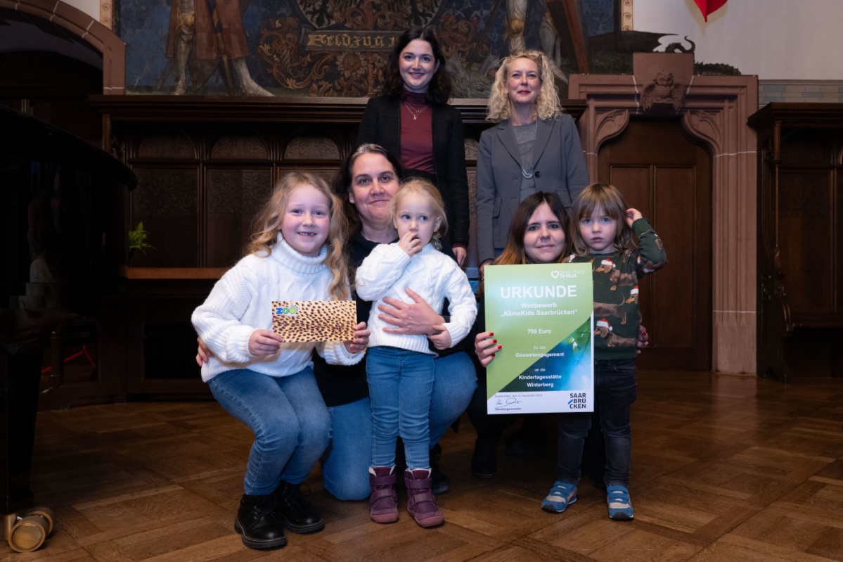 Kita Winterberg Preisübergabe an die Kita Winterberg. Zu sehen sind drei Schüler welche die Urkunde halten und eine Betreuerin der Kita, sowie zwei Jurymitglieder.