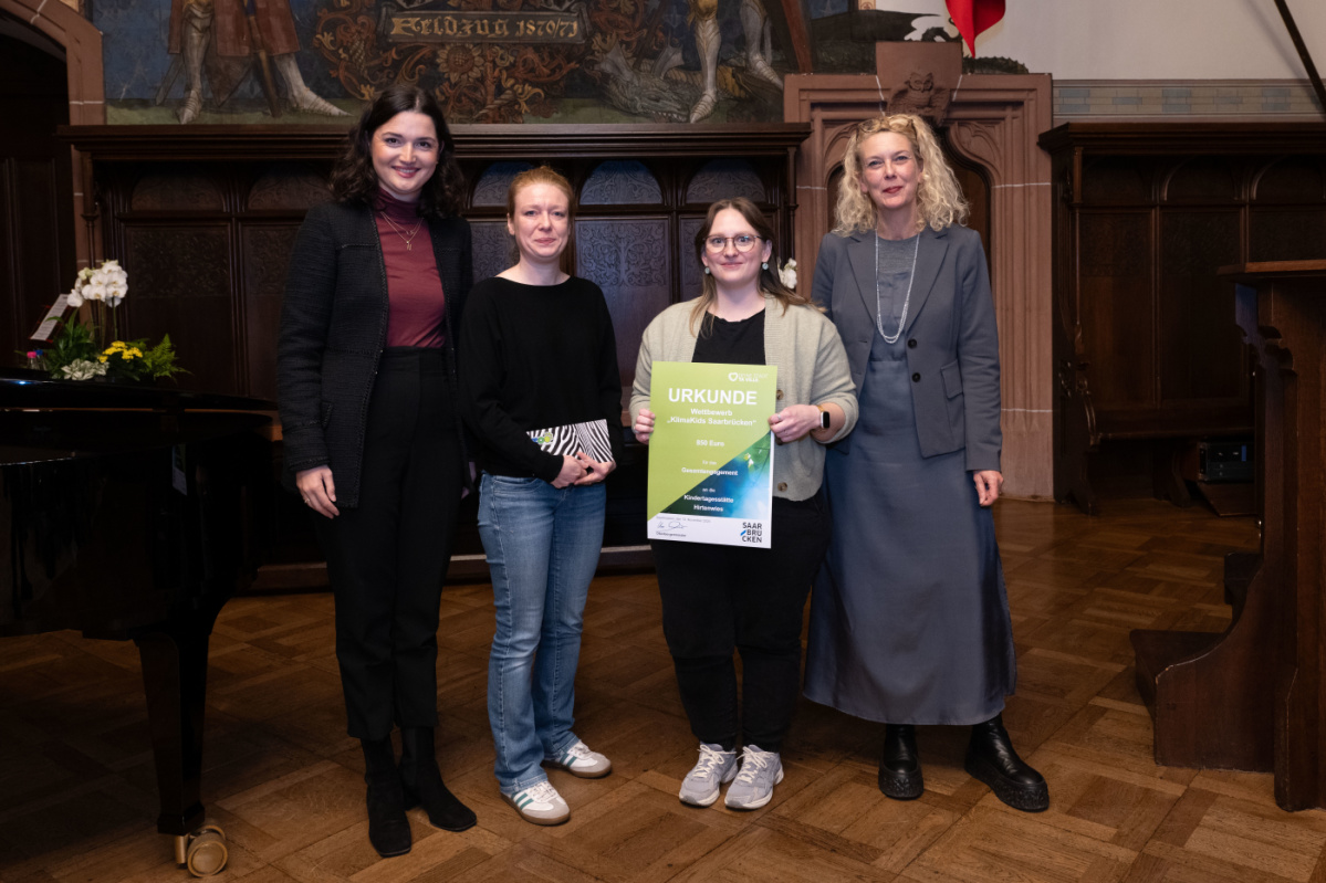 Kita Hirtenwies Preisübergabe an die Kita Hirtenwies. Zu sehen sind zwei Betreuerinnen der Grundschule die die Urkunde halten, sowie zwei Jurymitglieder.