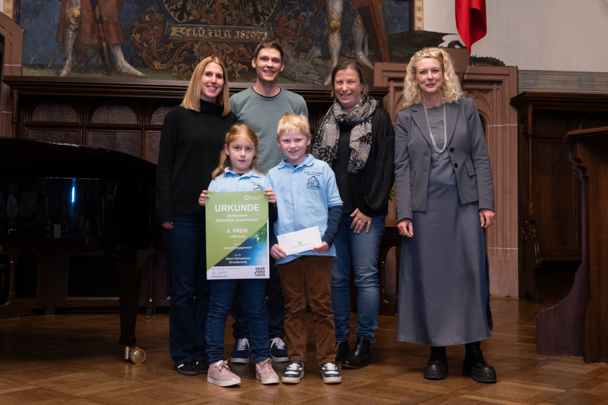 Platz 5 - Albert Schweitzer Grundschule Preisübergabe des fünften Platzes an die Grundschule Albert Schweitzer. Zu sehen sind zwei Schüler welche die Urkunde halten und zwei Betreuer der Grundschule, sowie zwei Jurymitglieder.