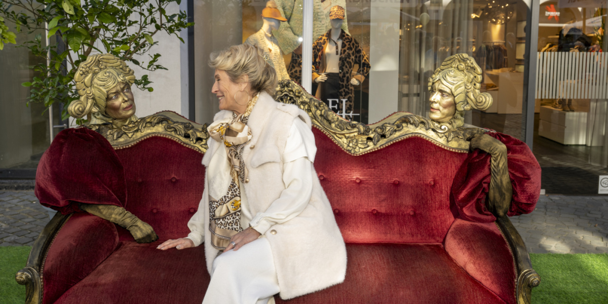 Frau auf rotem Sofa zwischen goldenen Figuren