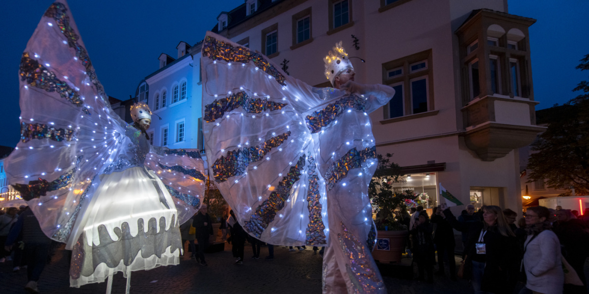 Zwei Stelzenläufer in leuchtenden Kostümen bei Nacht