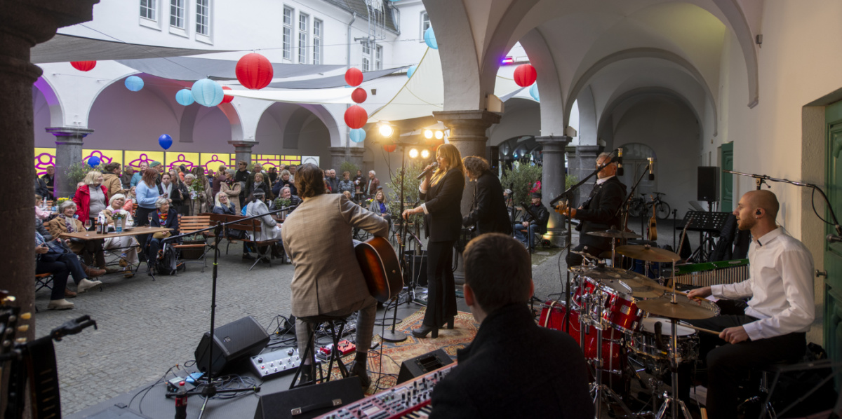 Band spielt im Hof, Publikum sitzt an Tischen