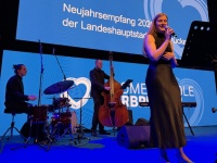 Neujahrsempfang der Landeshauptstadt 2026 Eine Band auf einer Bühne, dahinter eine Leinwand mit blauem Motiv